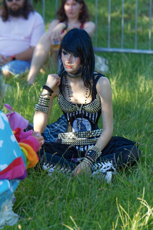 12 - Person dressed in punk fashion style, featuring layered studded belts and wristbands, and black combat boots